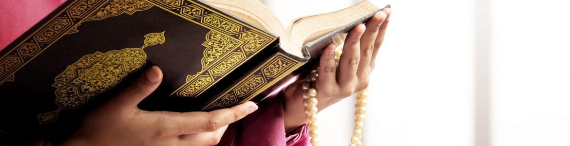 Muslim woman in a veil holding prayer beads and the Quran on the mosque